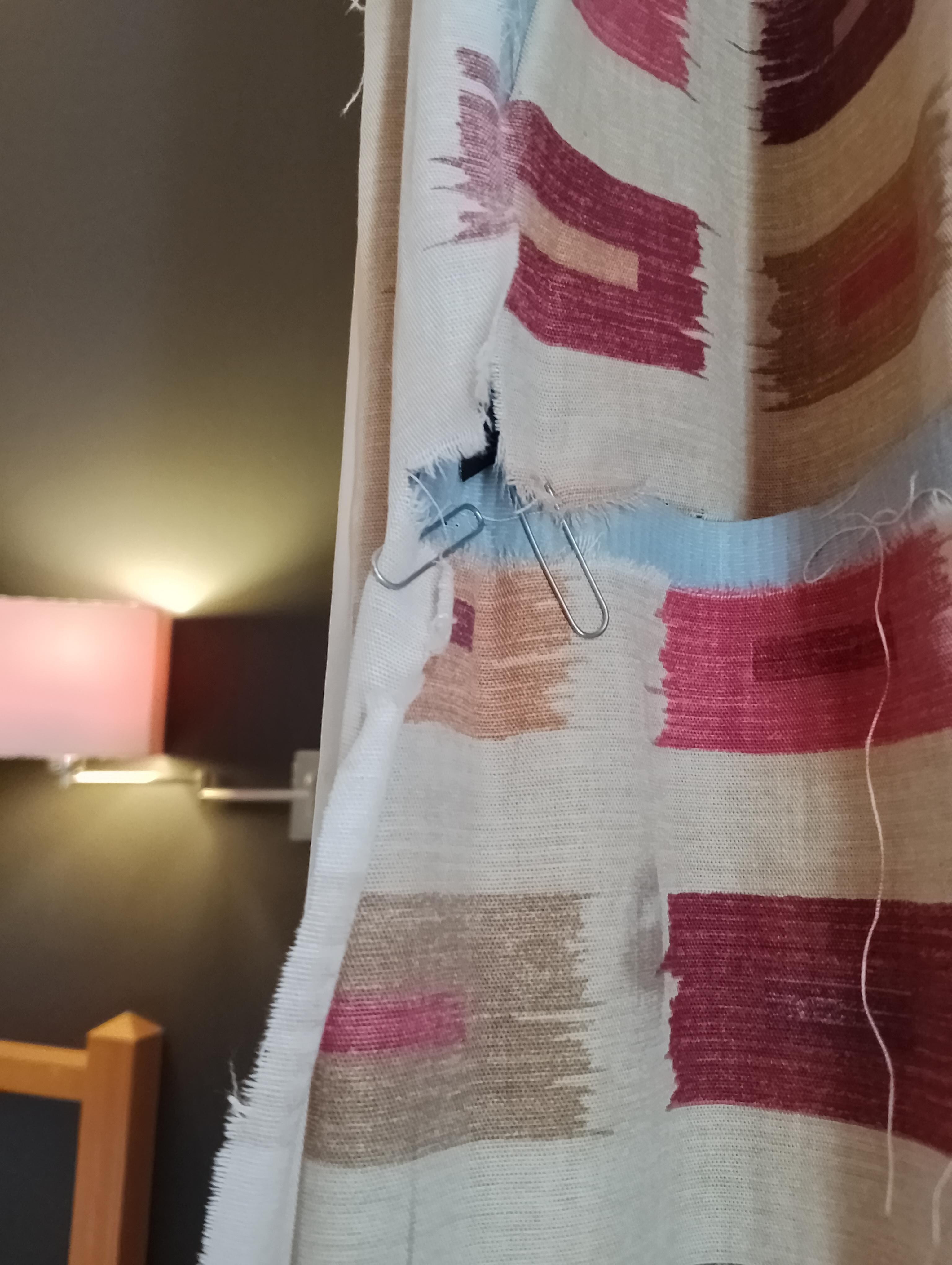 Torn curtains held together with paperclips.