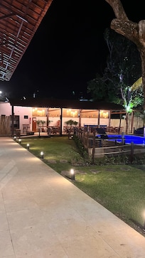 Pousada a noite com a piscina iluminada fica um charme
