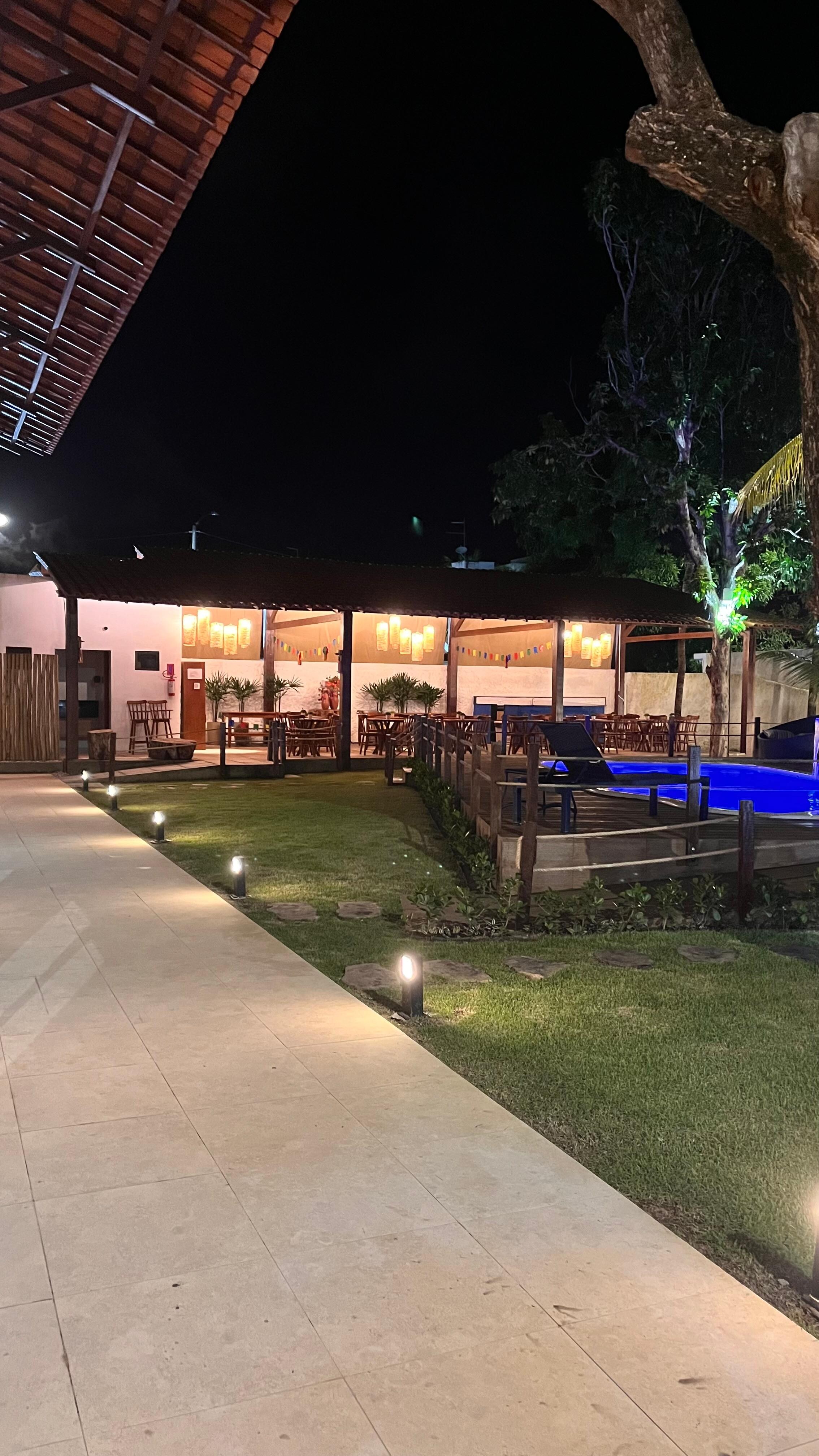 Pousada a noite com a piscina iluminada fica um charme