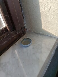 Cobwebs and beer caps in front of open window