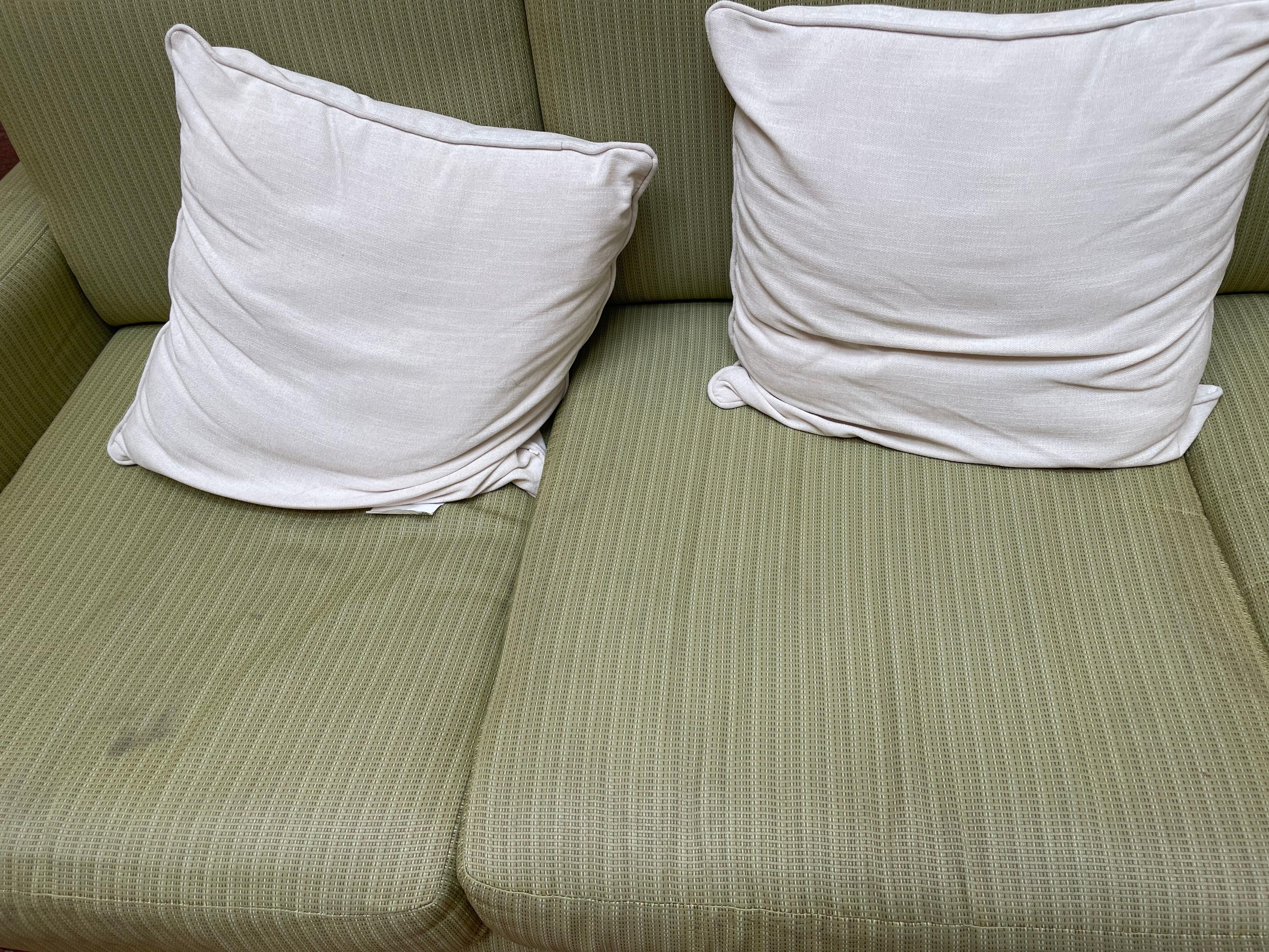 Lobby couch. Filthy green couch cushions. Haphazard throw cushions.