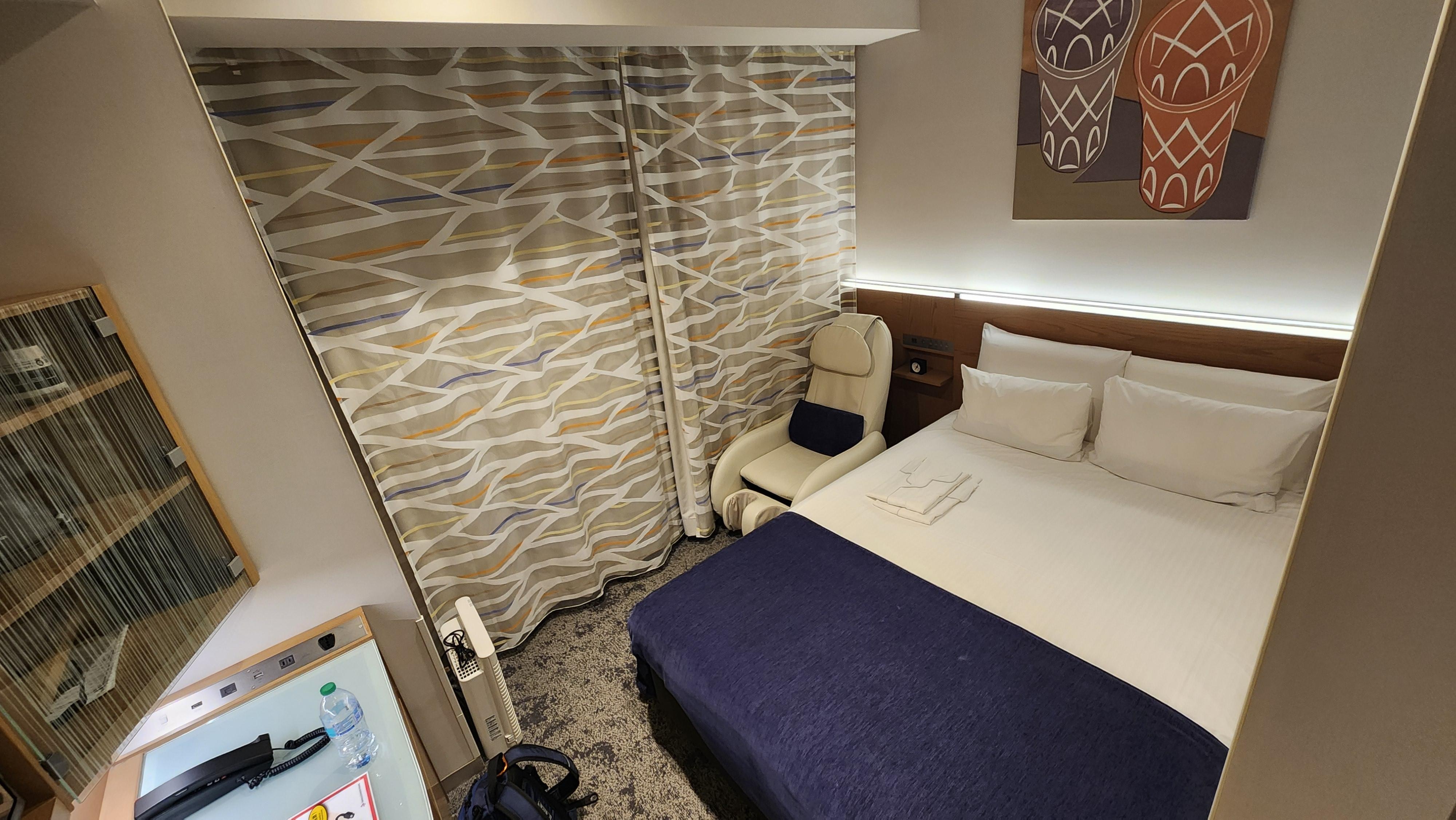 The "twin" bed, sufficient but placed against the wall on one side.