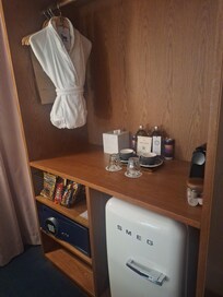 Drink station, safe, and refrigerator that is full of both alcoholic and non-alcoholic options in room