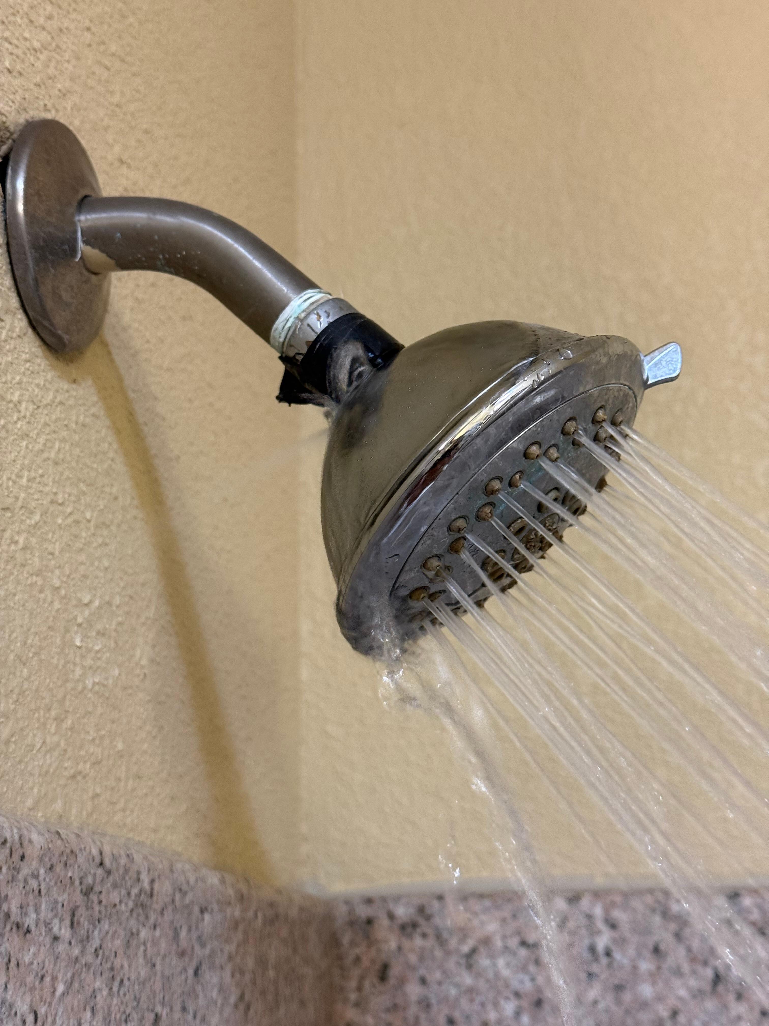 Water spraying out the side with black electrical tape on the shower-head. 