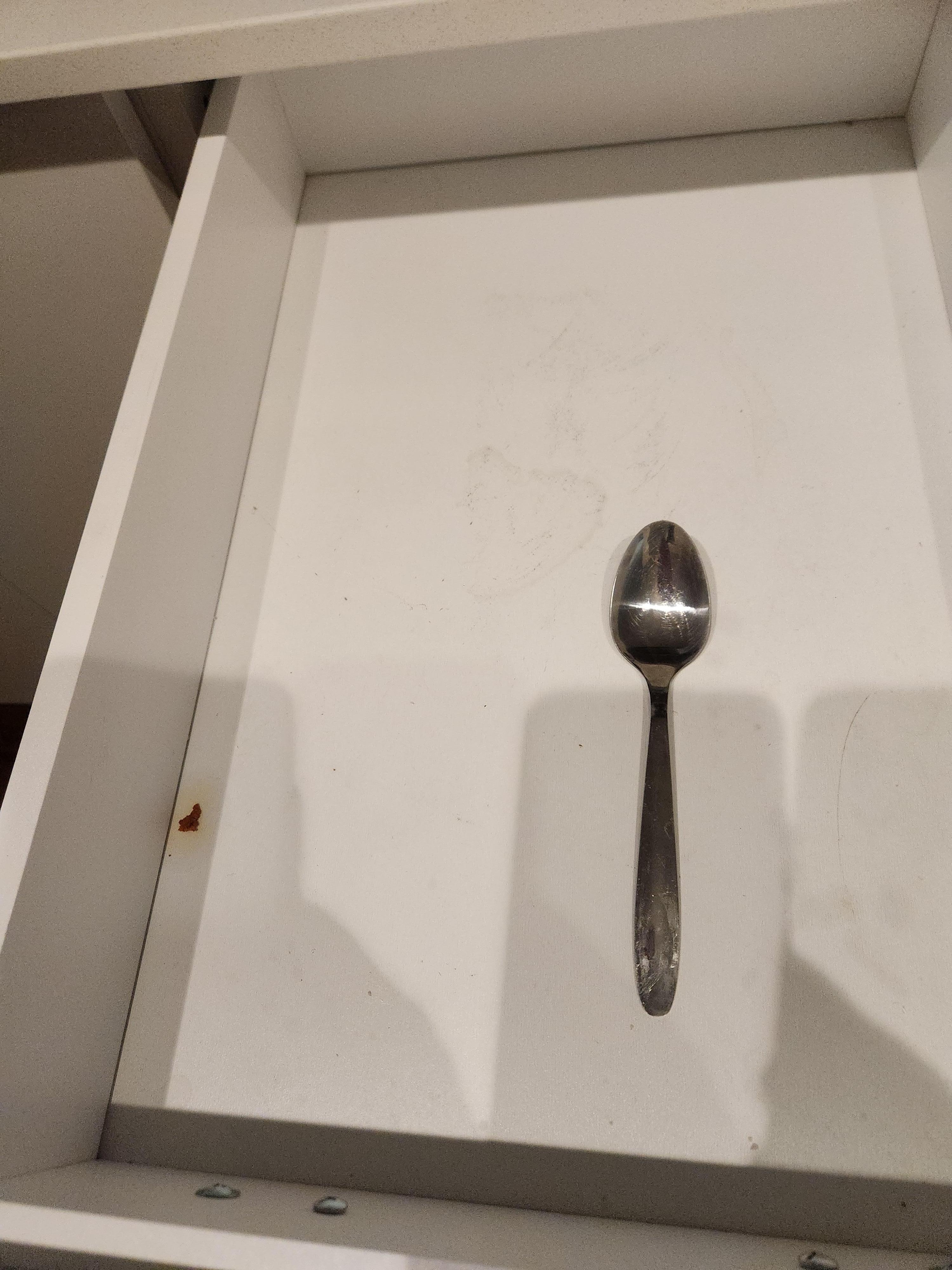 Dirty drawer with one spoon in it. 