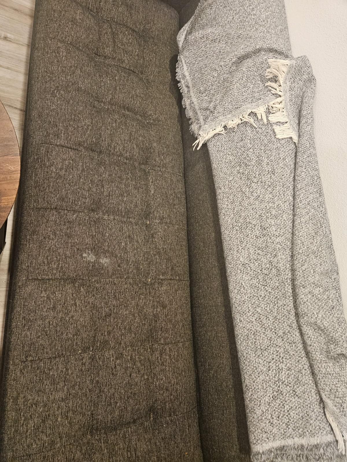 Stained couch, covered by blanket.