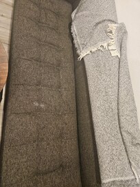 Stained couch, covered by blanket.