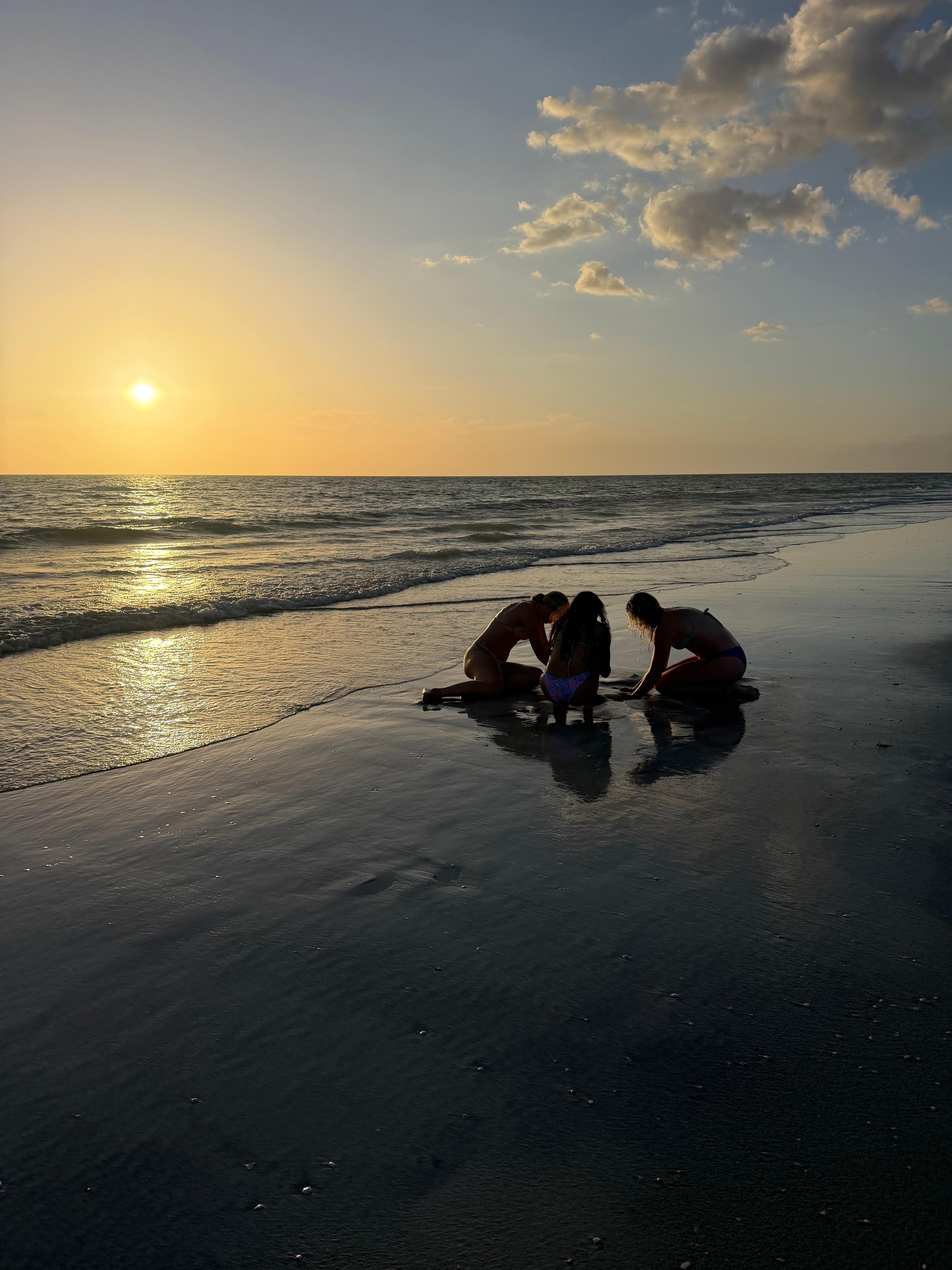 The girls digging playing in the sand. 