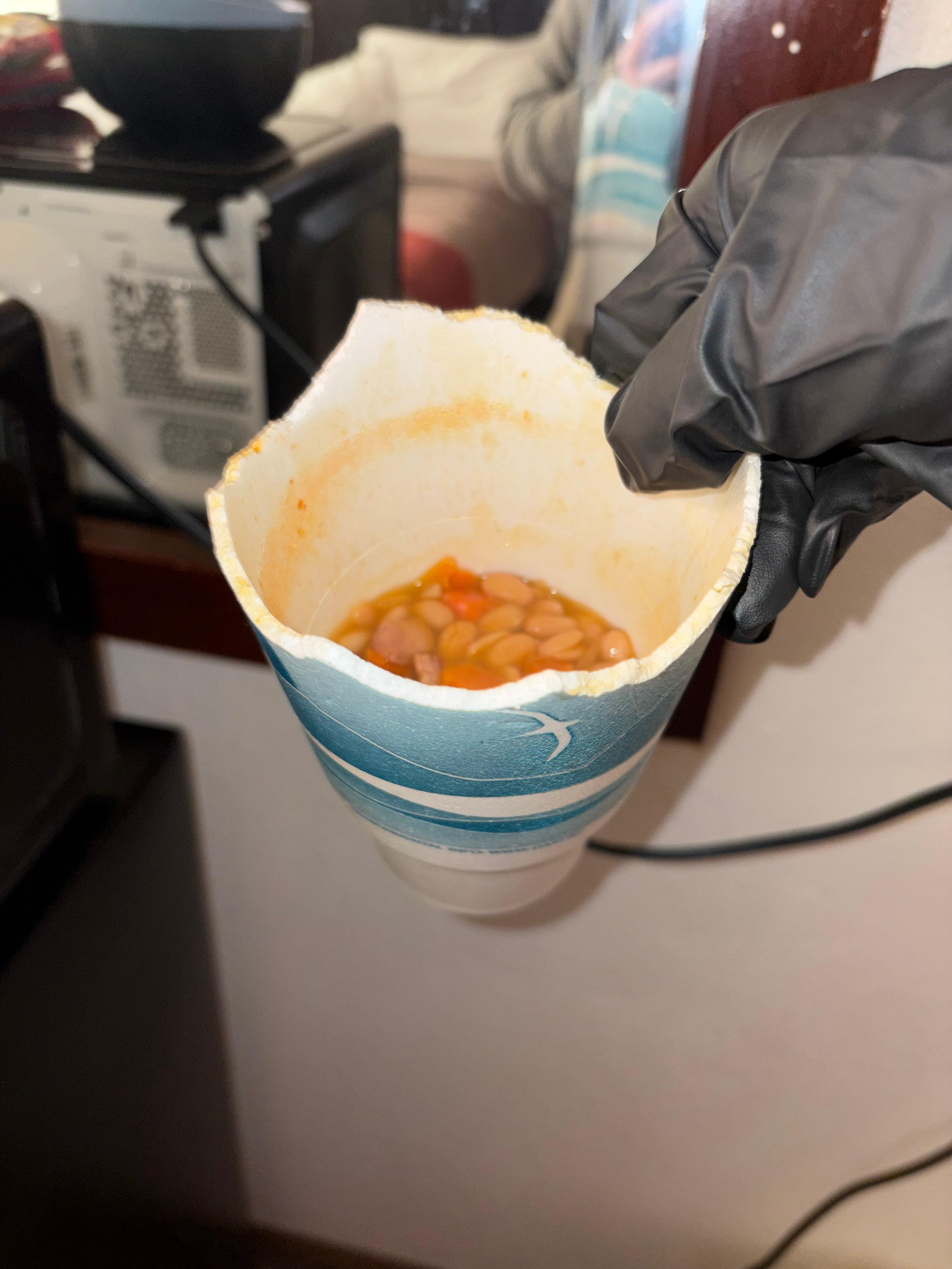 The half torn styrofoam cup with the food in it 