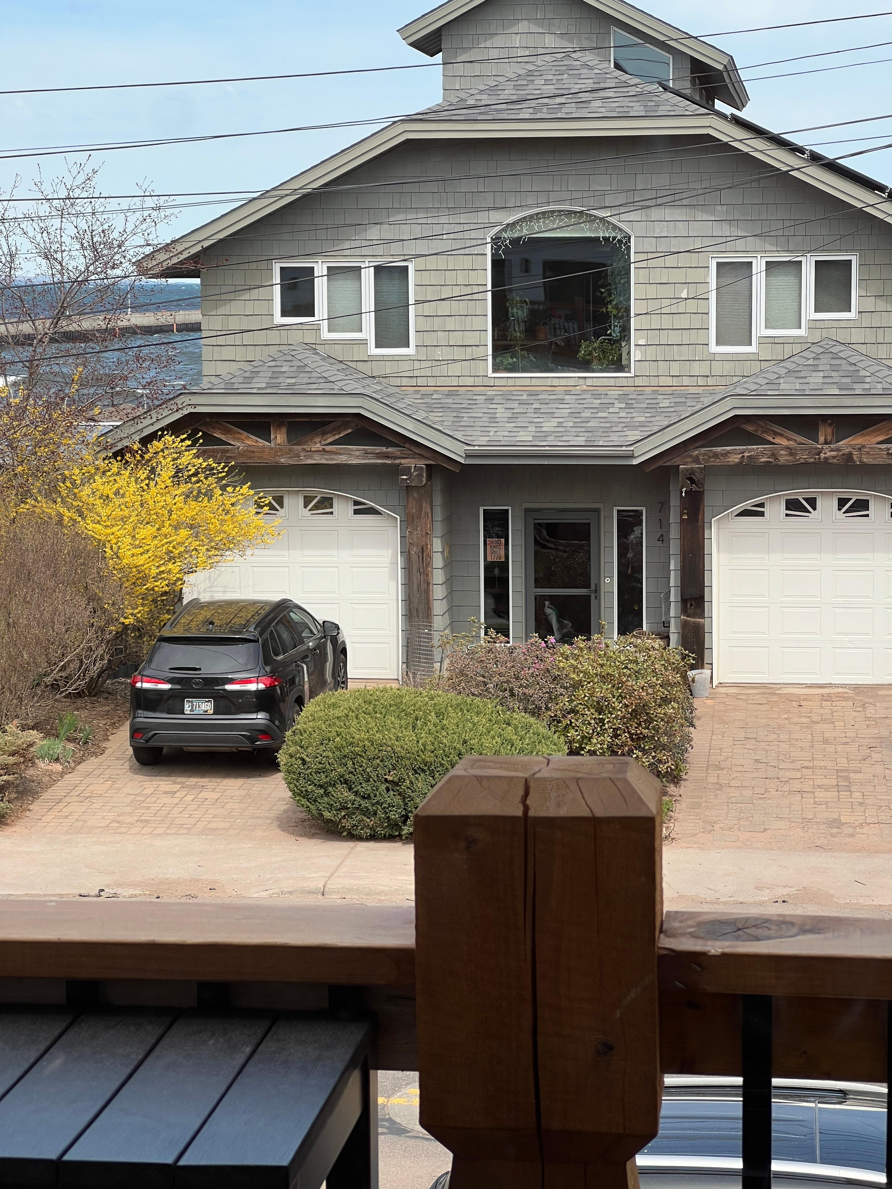 View straight out front with big lake visible, either side of a well kept home that has beautiful gardens