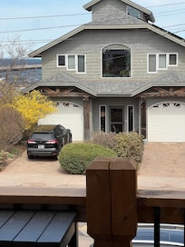 View straight out front with big lake visible, either side of a well kept home that has beautiful gardens