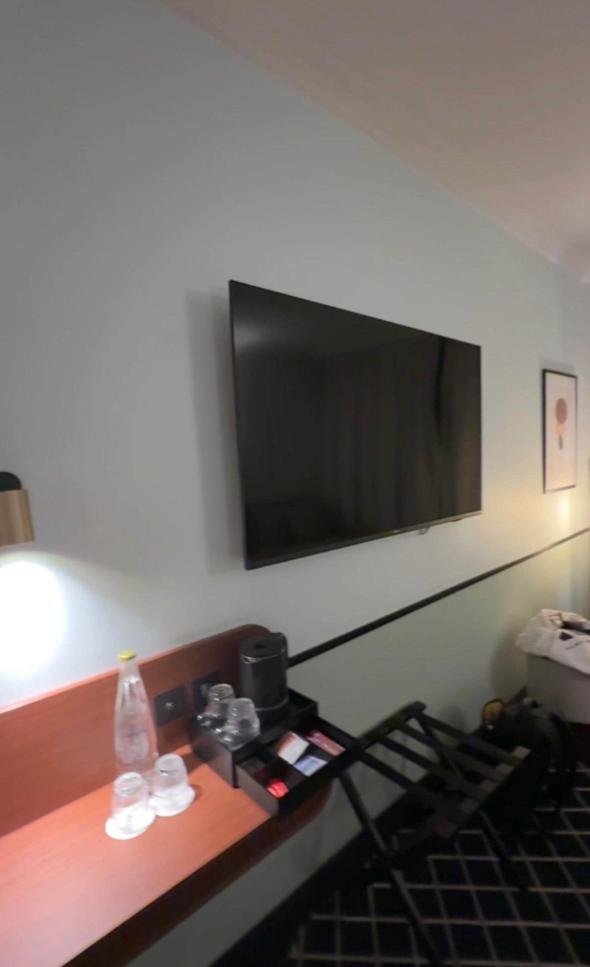 Televisão smart grande, mesa para trabalho e máquina de água quente, chás e água e copos 