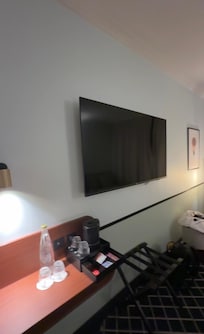 Televisão smart grande, mesa para trabalho e máquina de água quente, chás e água e copos
