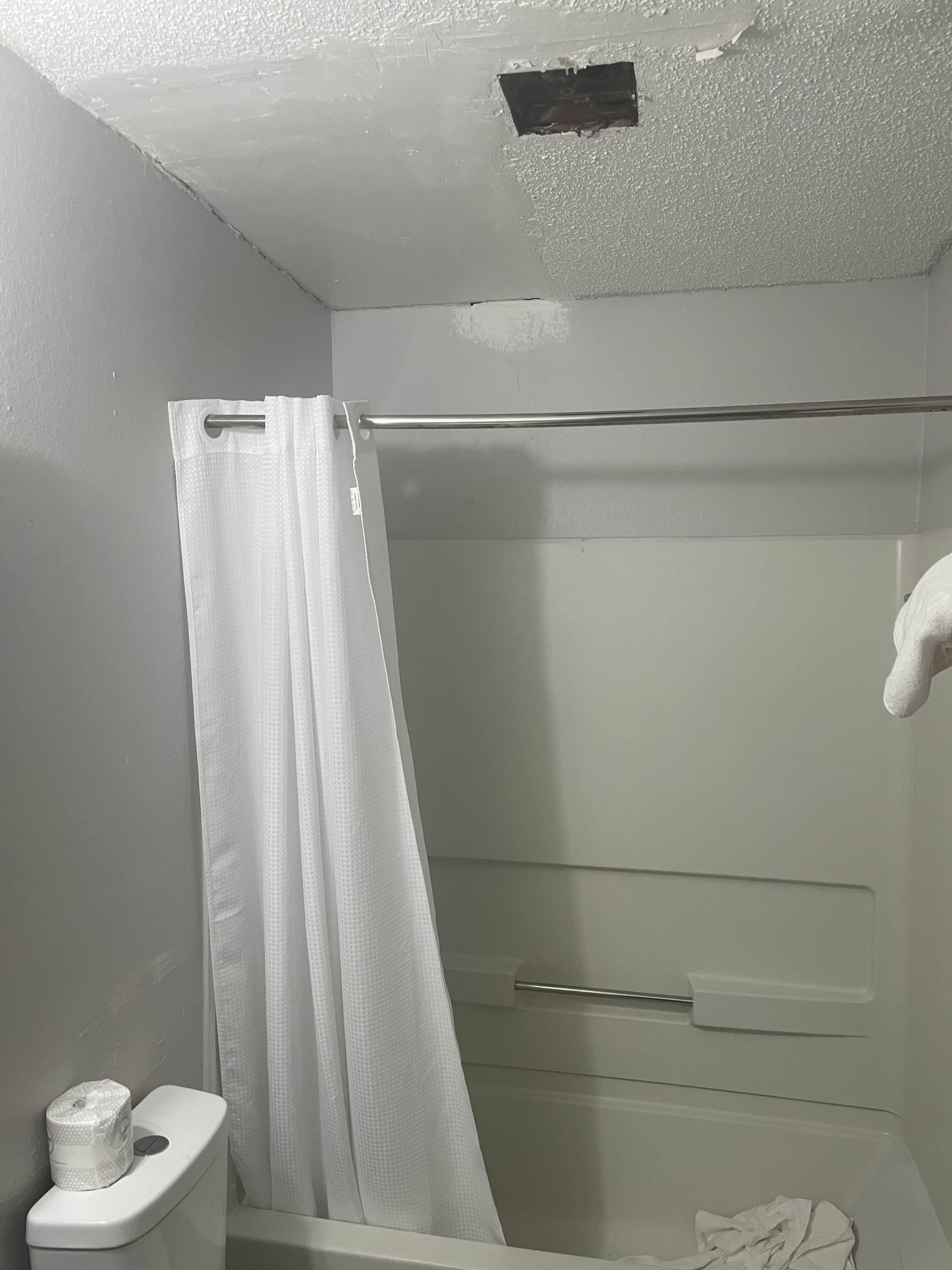 Bathroom. Exposed fan blade. Cracked and broken tiles, walls, and door.