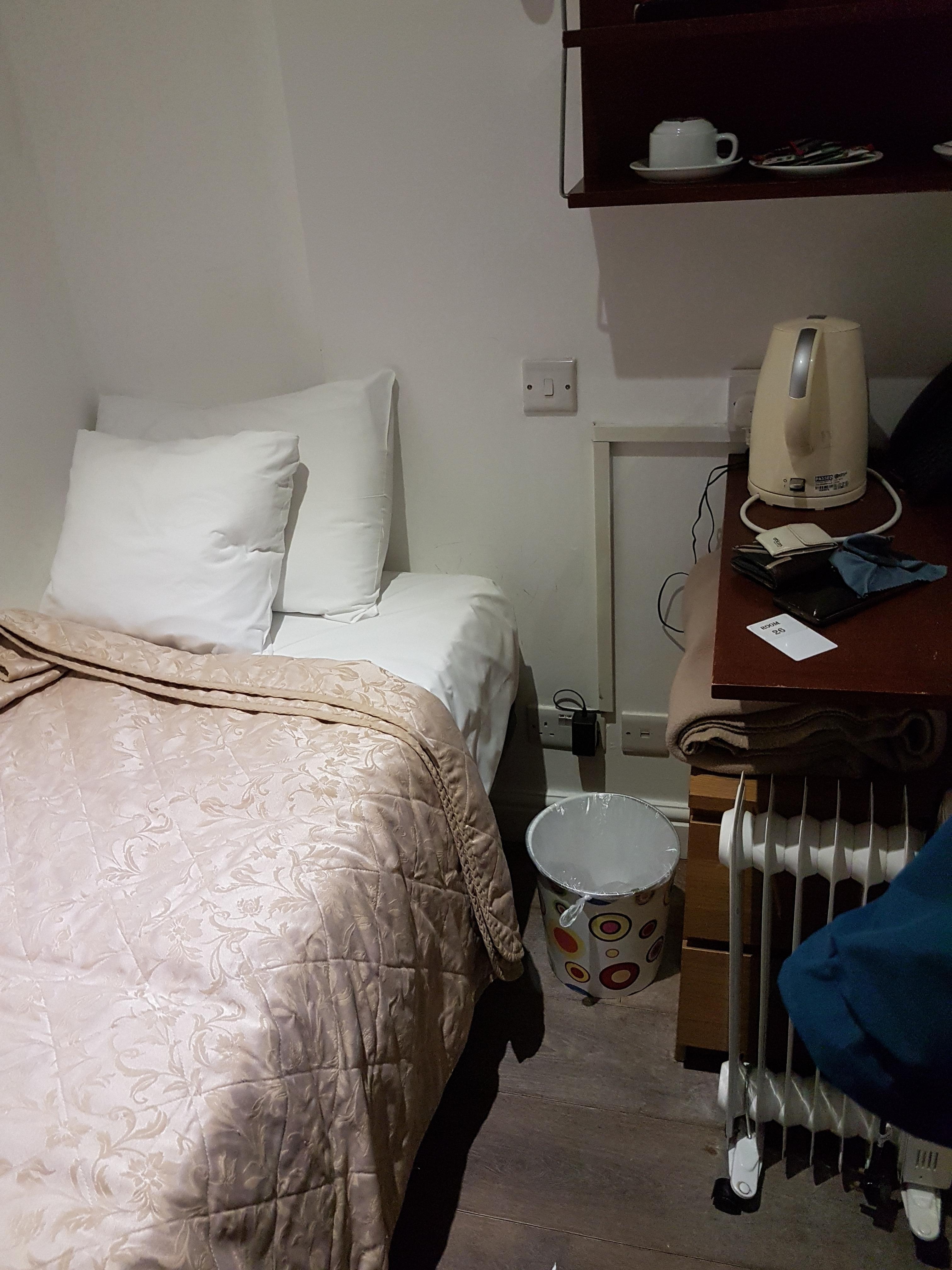 A narrow metal cot up against the wall on 3 sides