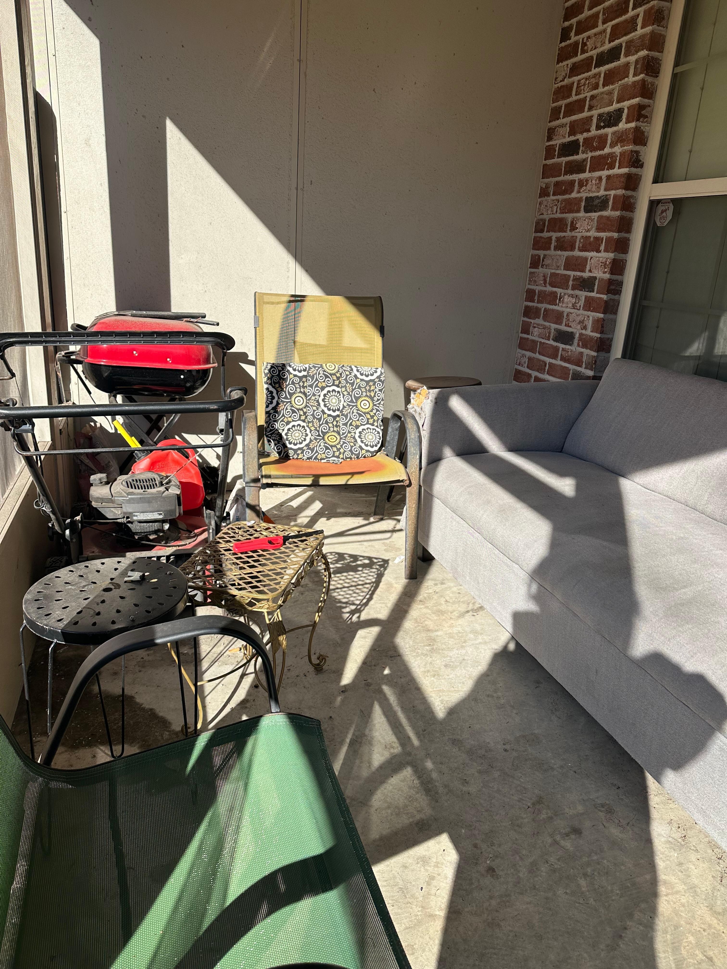 Cluttered back screen porch with stained couch.