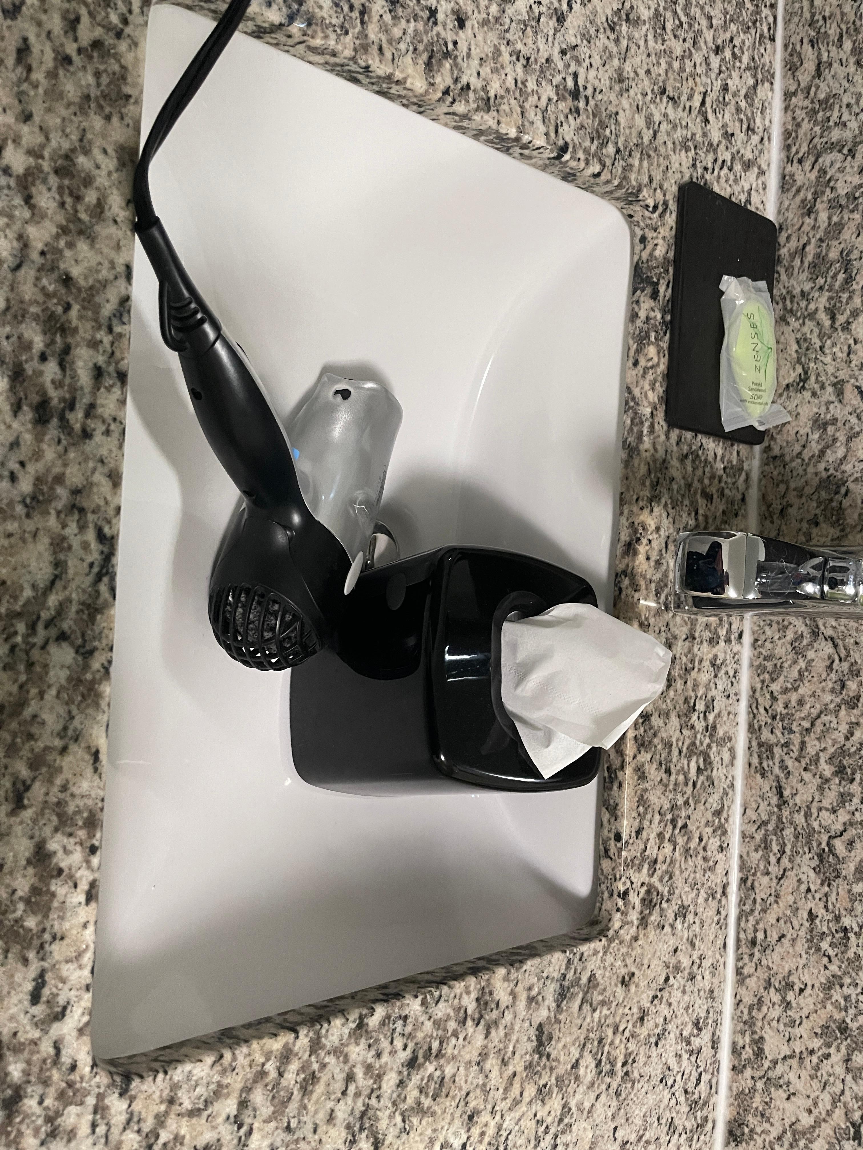 Hair dryer and tissues in sink 