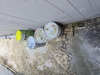 Old paint buckets on side of house filled with rancid water and trash