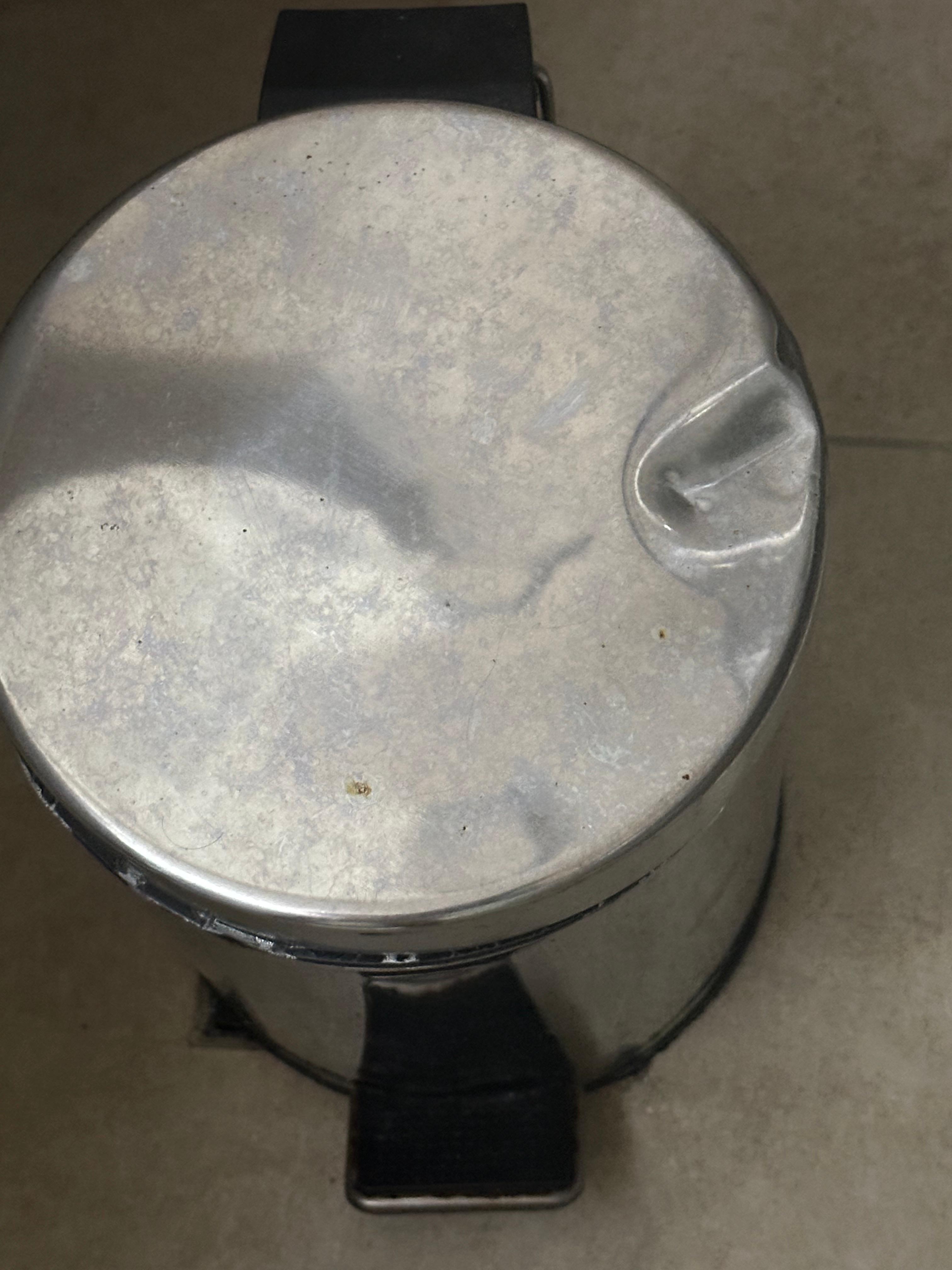 The lid of the bathroom trash can was badly dented.
