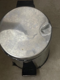 The lid of the bathroom trash can was badly dented.