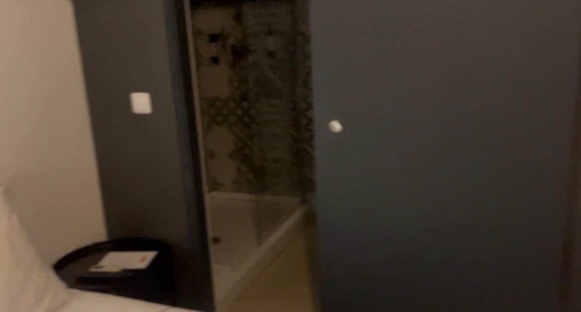 Porta de correr que da acesso ao banheiro. Banheiro tem secador, kit de primeiros socorros, é amplo, mas não possui Box em toda a parte do chuveiro.