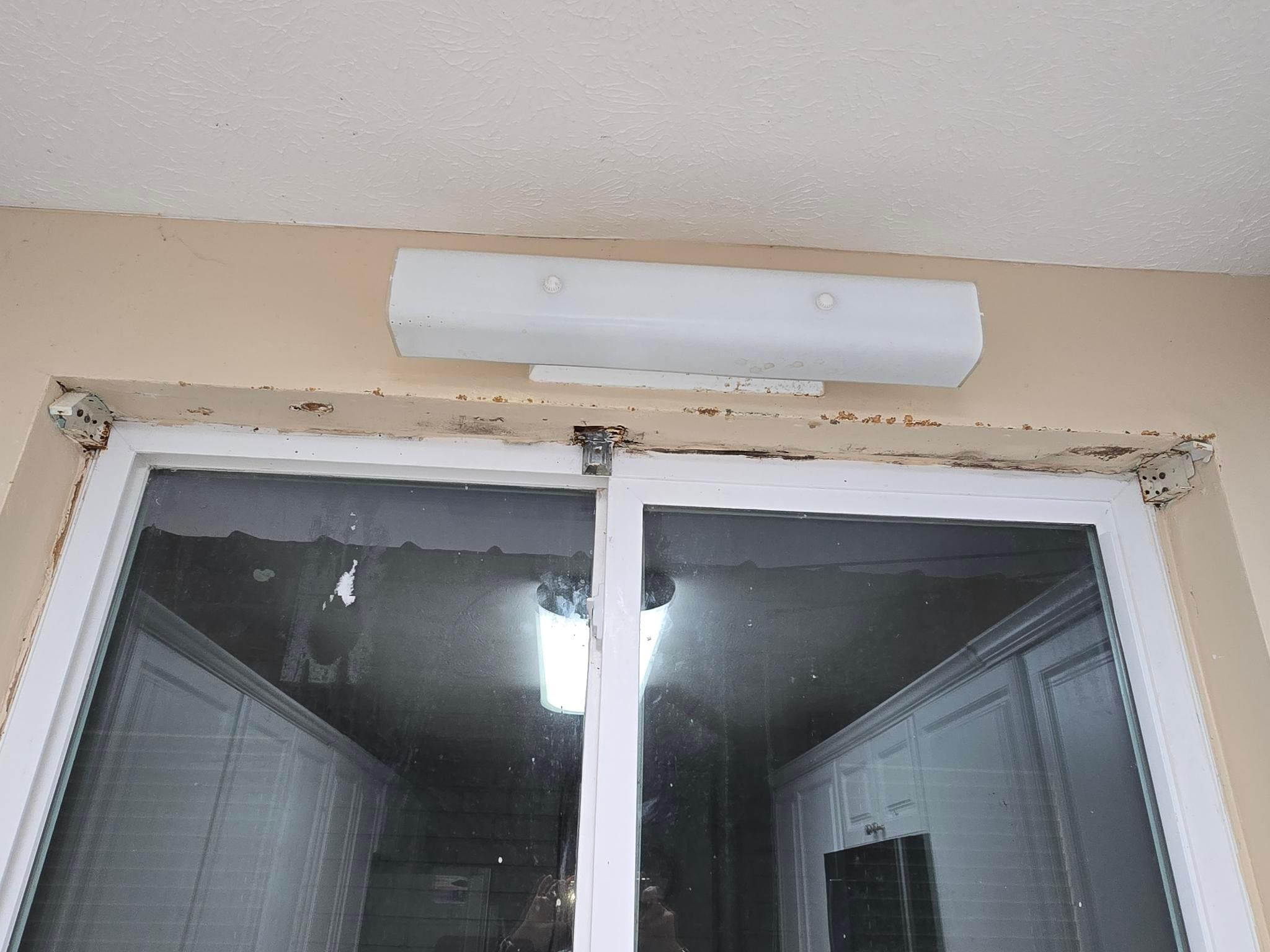 Cracked paint around kitchen window with mold and dirty light fixture, blinds gone.