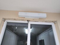 Cracked paint around kitchen window with mold and dirty light fixture, blinds gone.