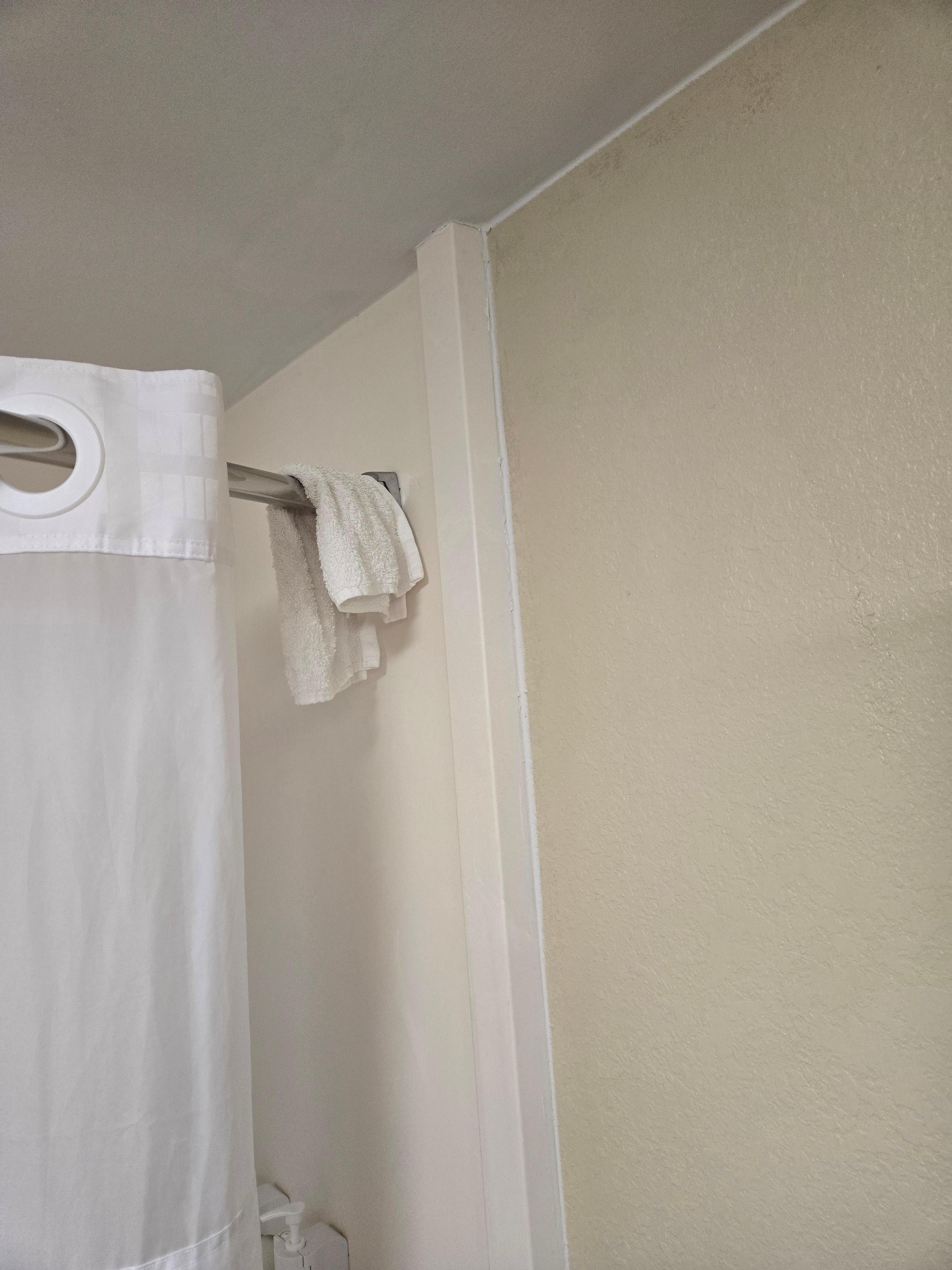 Leftover dirty washcloth hanging from shower rod.