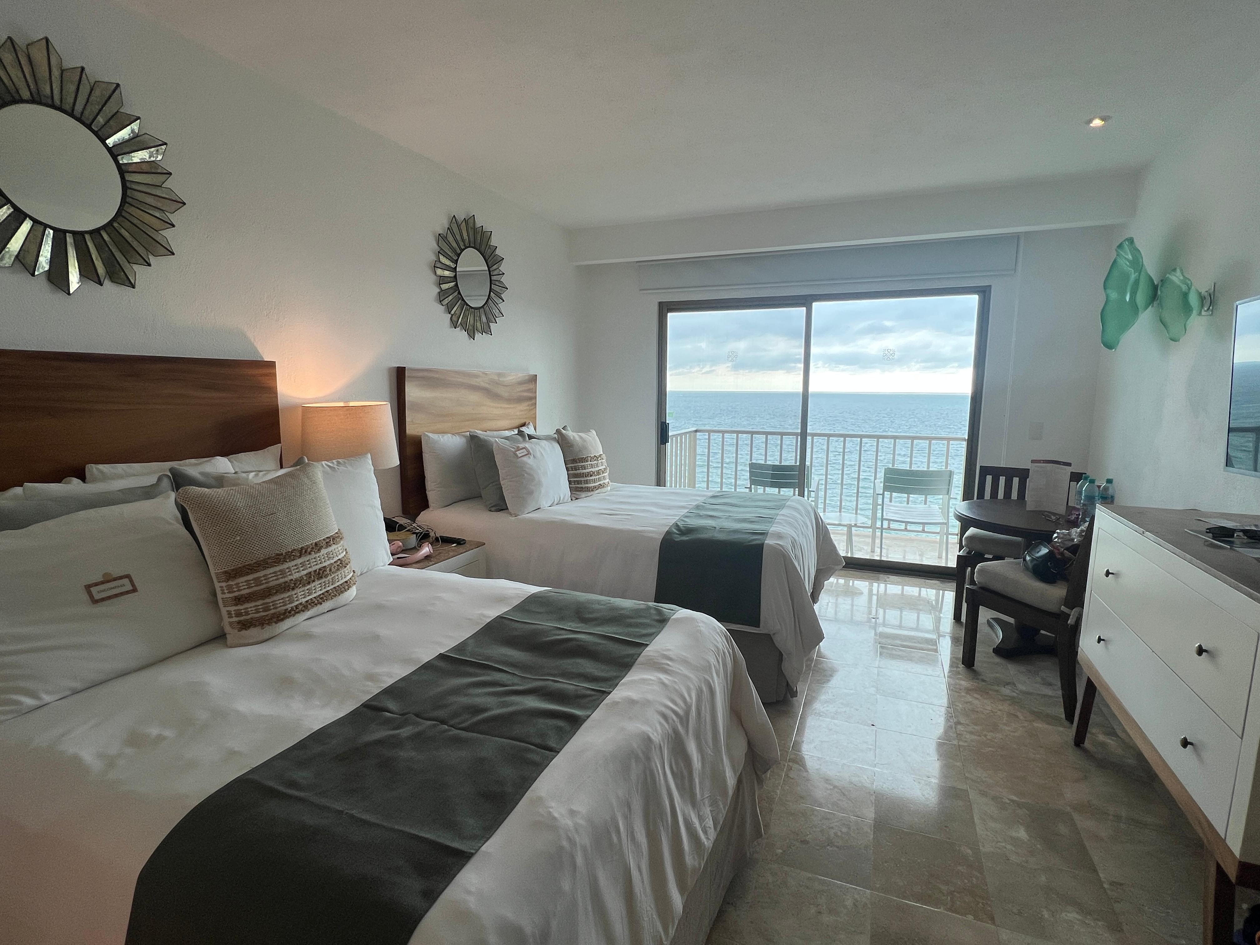 Two double beds in the room with a nice balcony with a view of the ocean