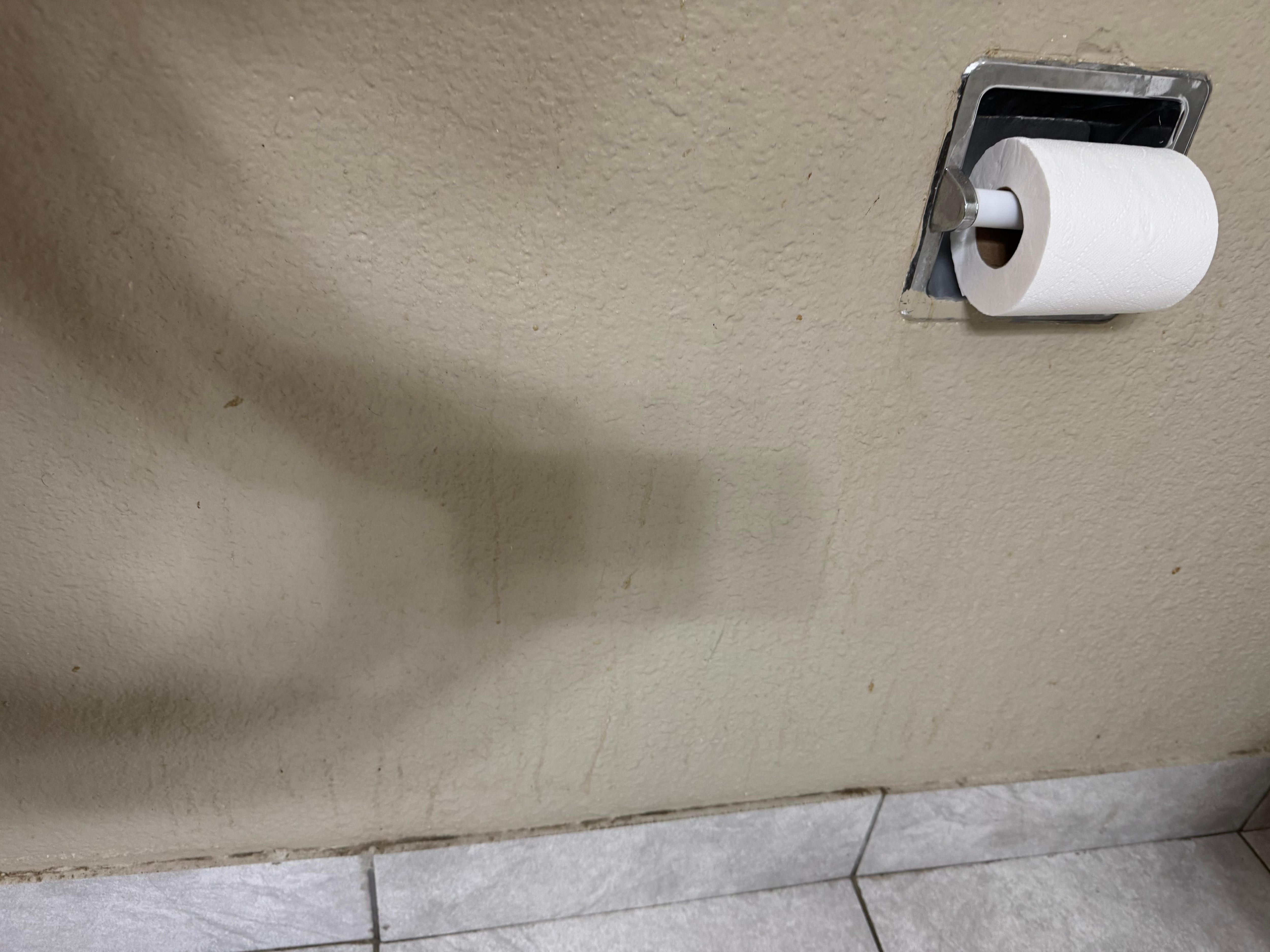 Dirty walls and floors in bathroom.