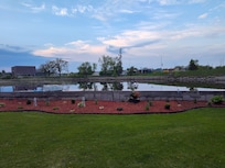 Closer view of lawn, landscaping, and river from the backyard chairs.