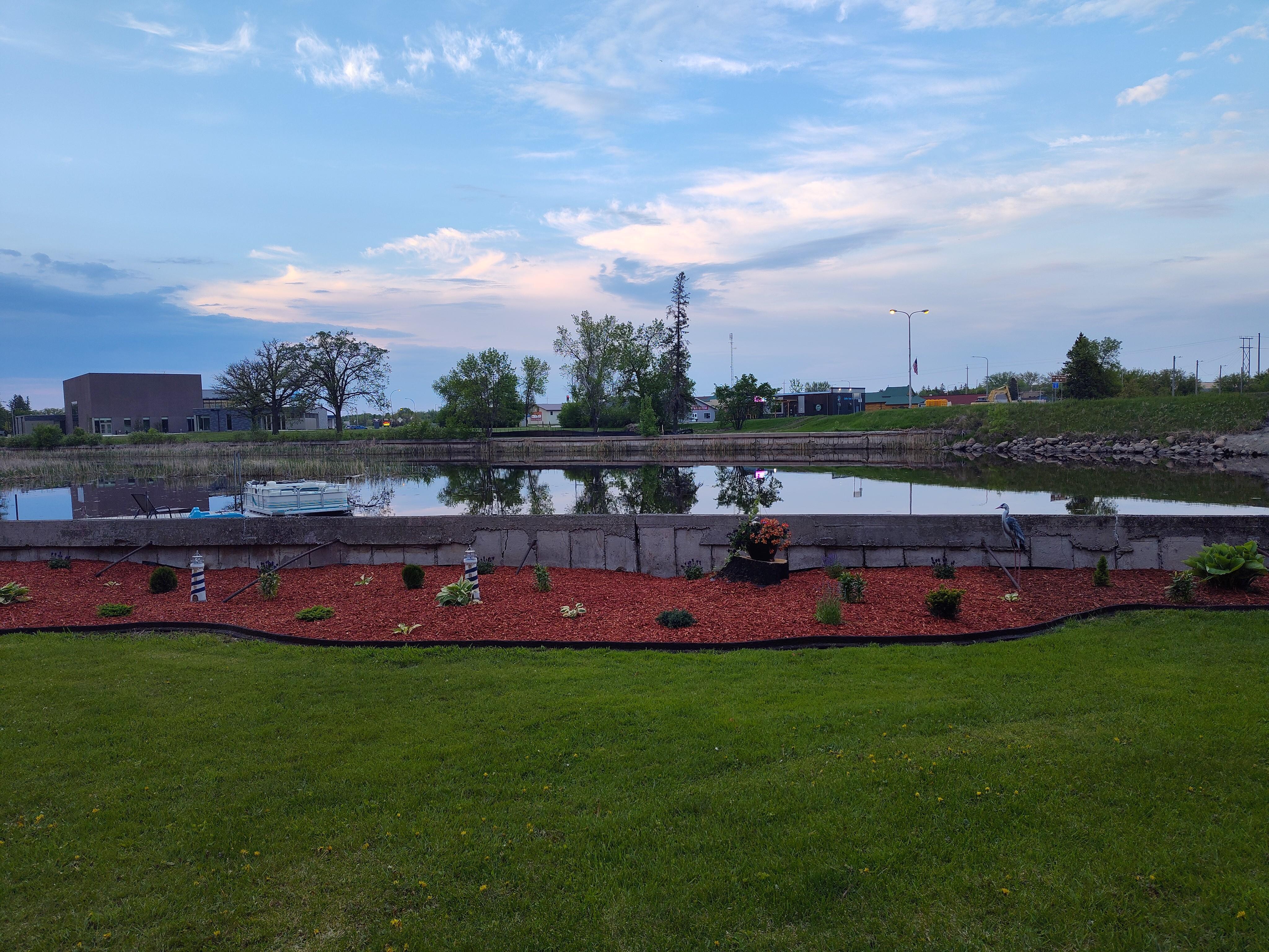 Closer view of lawn, landscaping, and river from the backyard chairs.