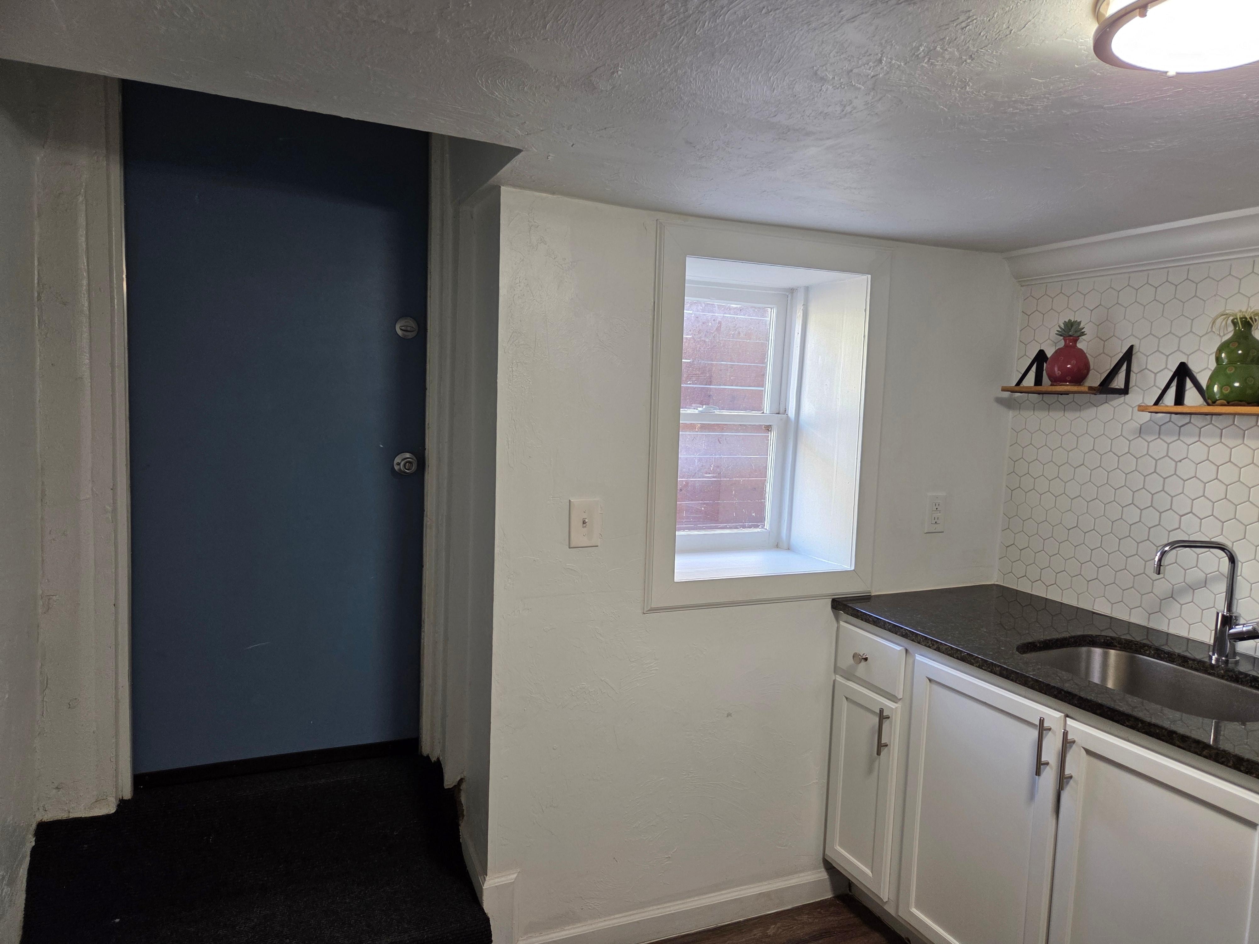 Exterior door to side yard/driveway with uncovered window.