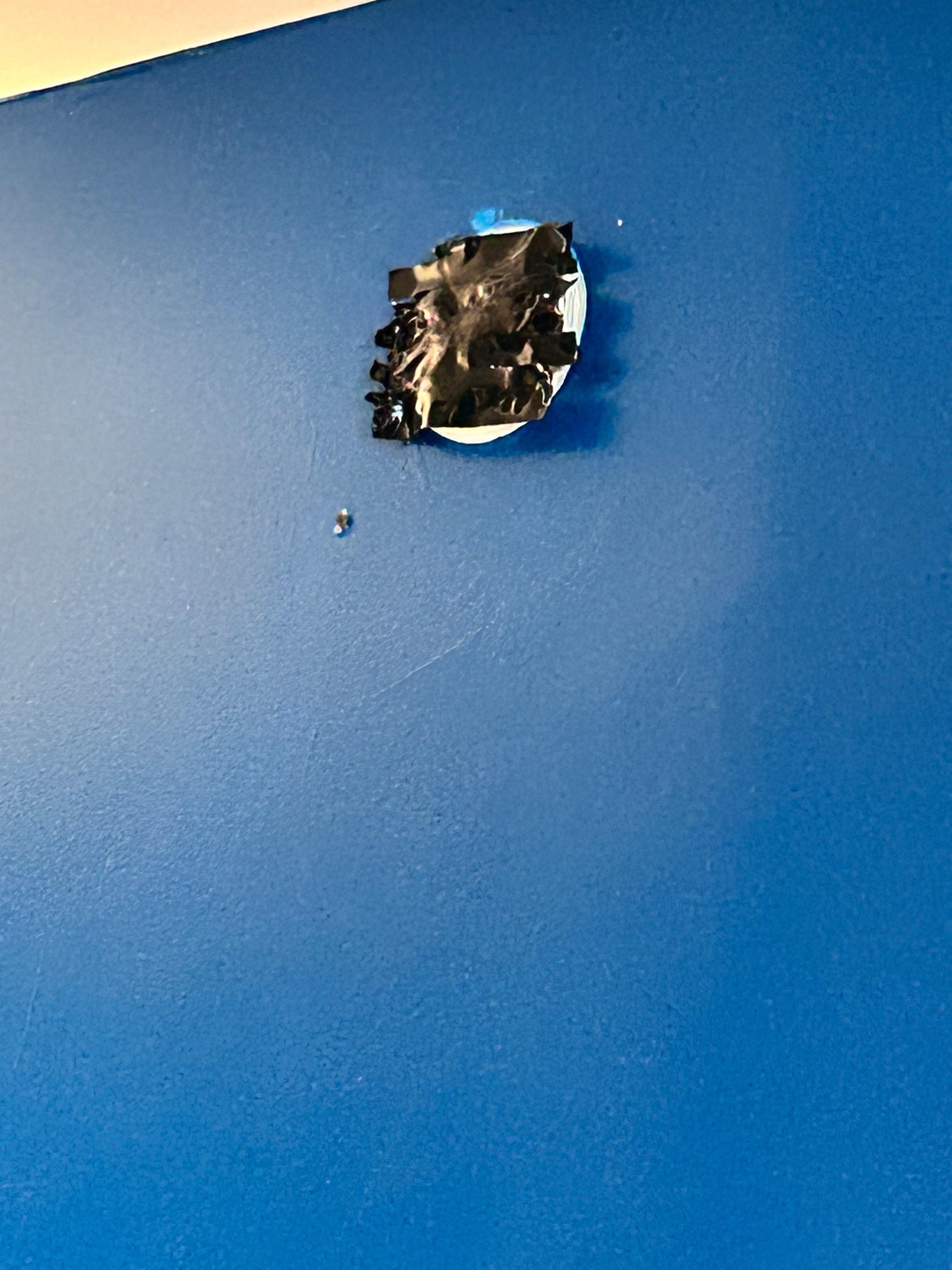 Hole in the wall covered with black electric tape.