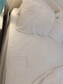 Stained mattress cover with no fitted sheets.