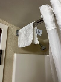 Used washcloth hanging on the shower curtain rod.