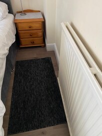 Small piece of carpet beside bed which slipped around