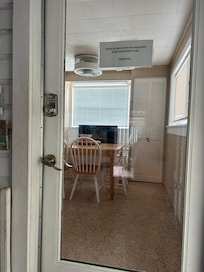 The coded entry door heading in to the dining and kitchen area. Fireplace under the window, above a bench.