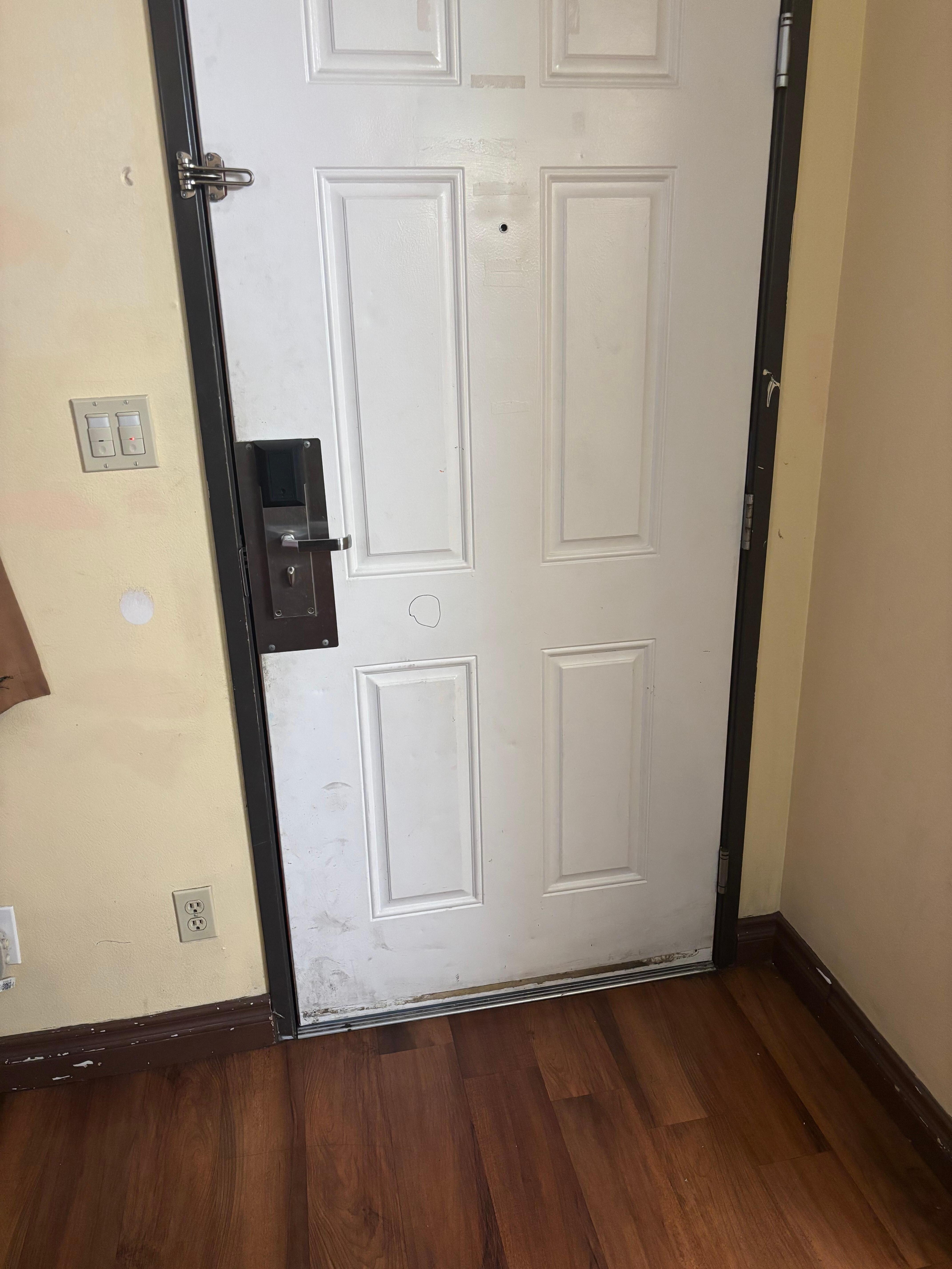 Door has drawing on it and a patched hole in the wall and door being dirty