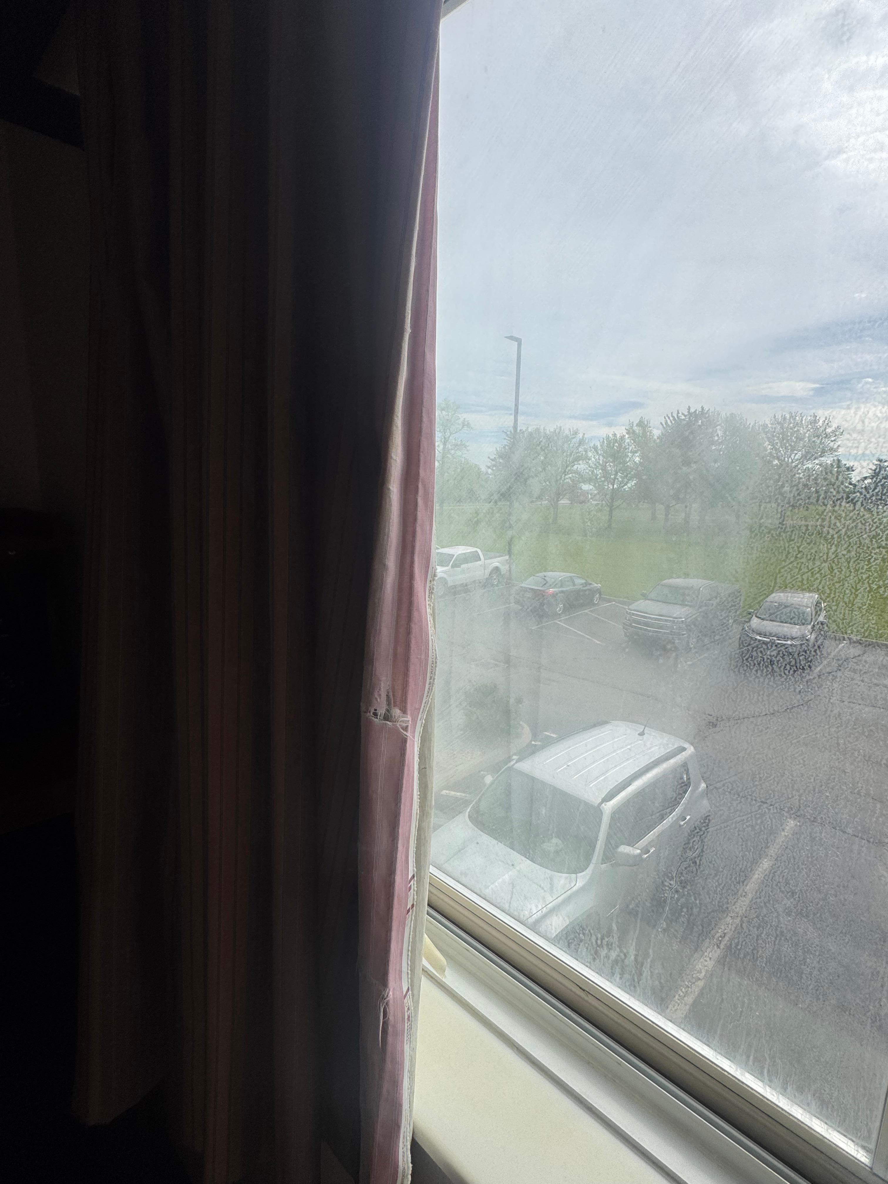 Dirty window with ripped up curtains