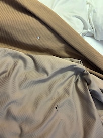 Ropa de cama vieja, con agujeros como de cigarro