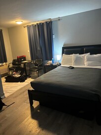 The bed and sitting area. Disregard personal belongings. Two chairs provided, digital hotel food service provided on a QR code sheet.