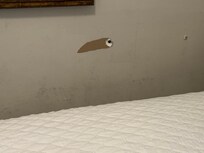 Holes and dirty walls next to the bed