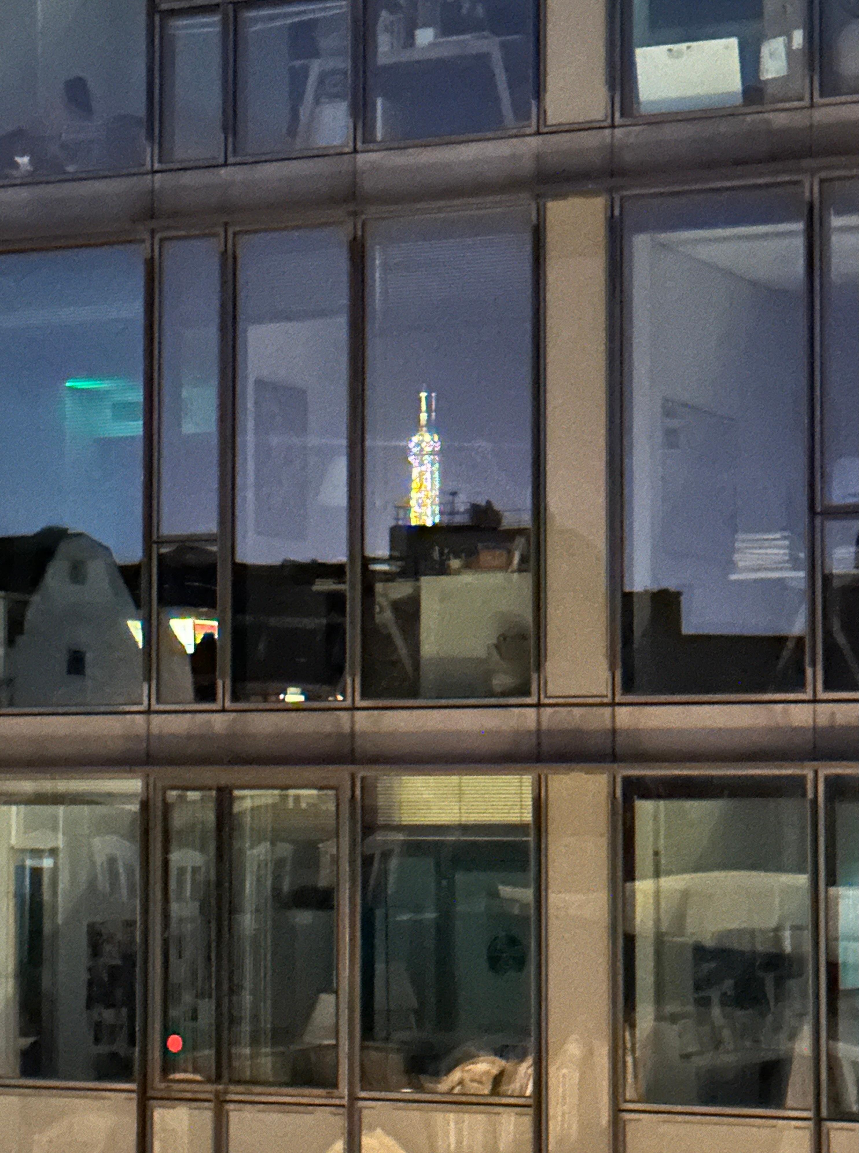 Reflection of Eiffel Tower in building windows across the street. 