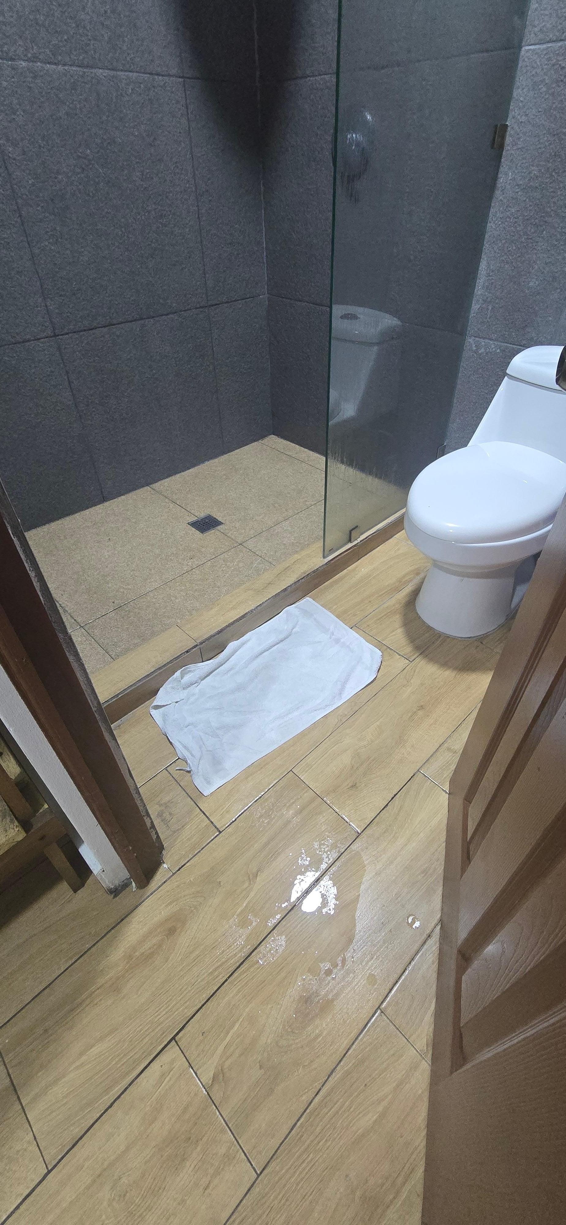 El baño sin puerta en la ducha ni cortina la puerta de entrada es todo lo que se habre el agua cae al piso