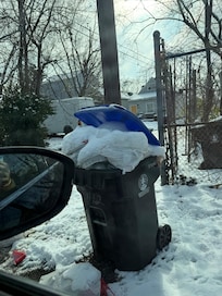 Garbage overflowing in front of gate and on road