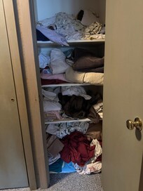 The linen closet looks like a bomb went off in it