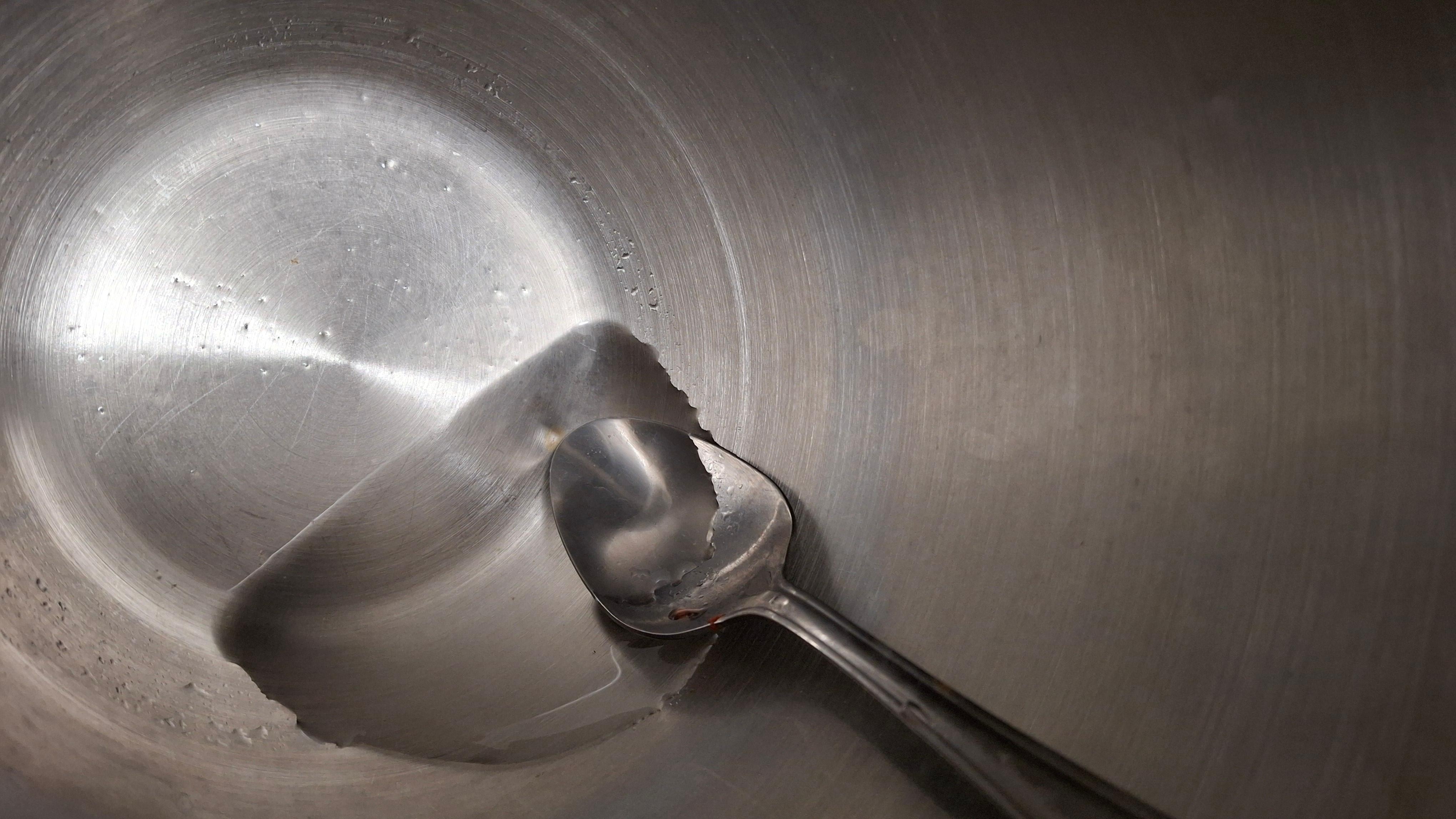 Uncleaned interior of ice bucket that had melted ice and a dirty spoon from the previous guest.
