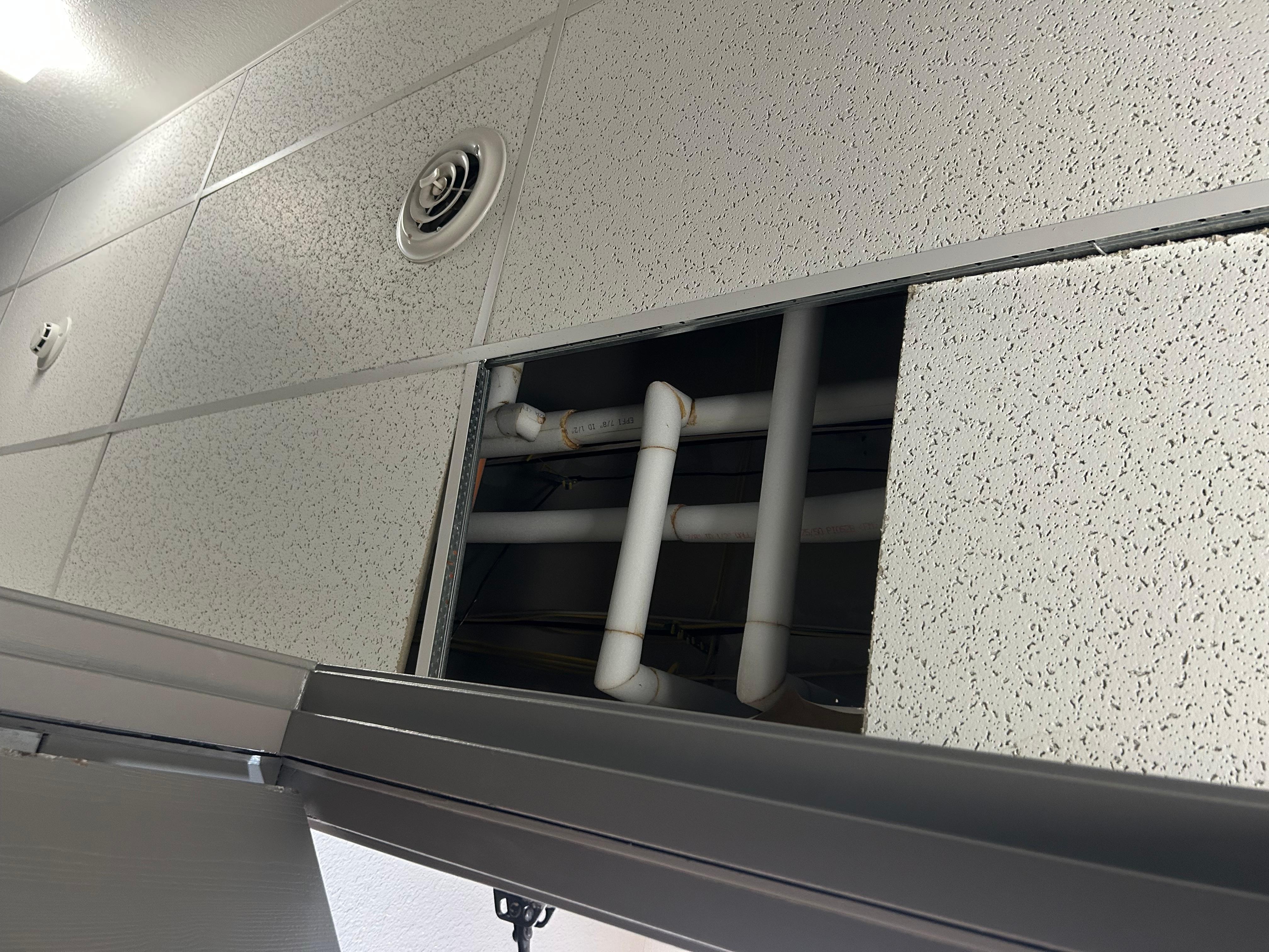 Pipes exposed on top of room door 102