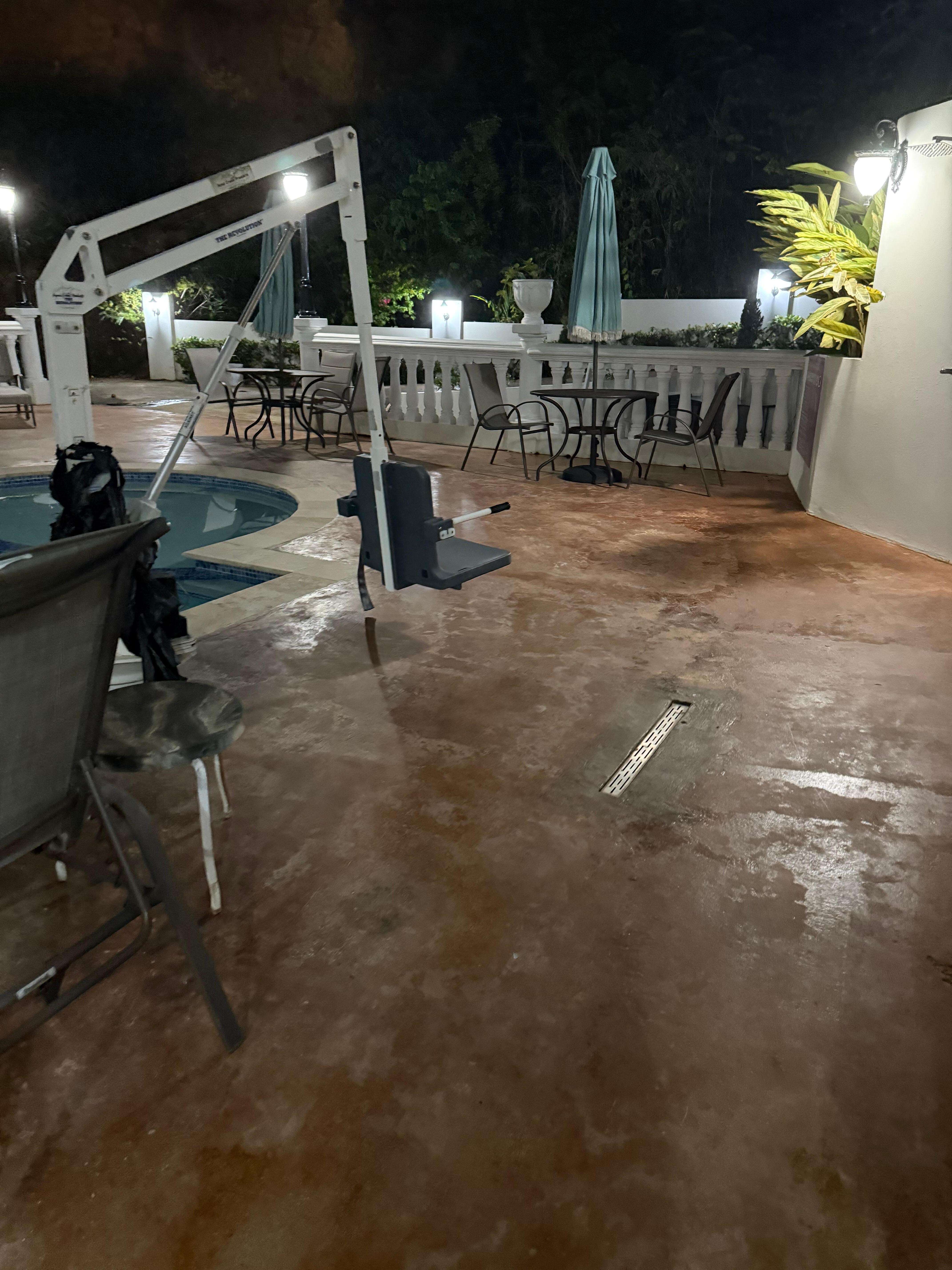 Plastic bags around handicap lift in pool and rusted furniture around pool